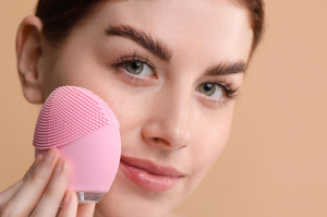 Woman using pink facial cleansing brush