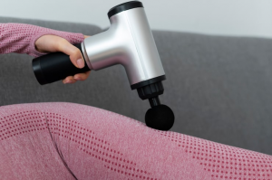 Woman using silver massage gun on leg