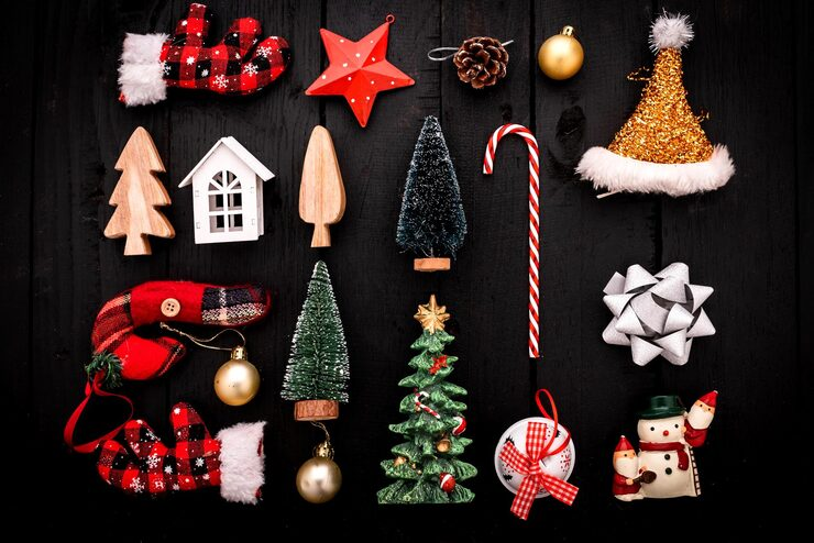 christmas ornaments including trees gloves a snowman and a candy cane arranged on a black wooden background
