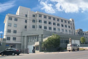 exterior of a multi storey building with cars parked outside under a blue sky