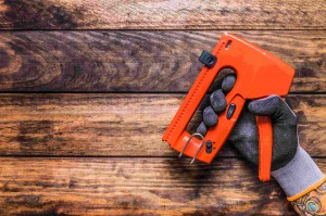 human-hand-holding-staple-gun-wooden-background