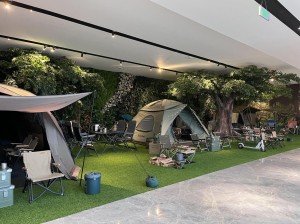 indoor camping display with tents chairs and greenery