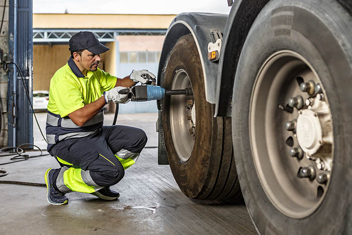 Male mechanic repairing car wheel